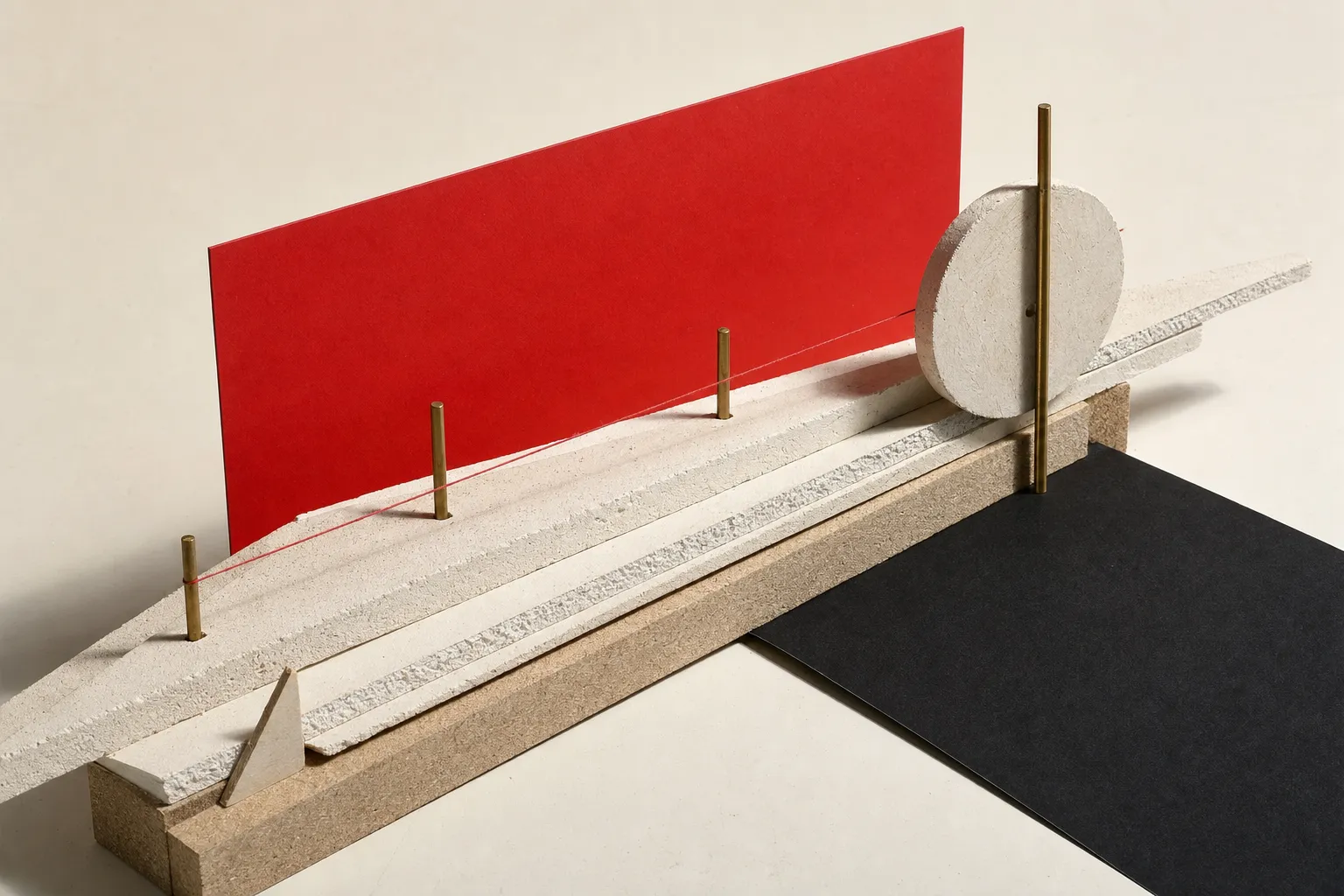 A study model of plaster slabs stacked and offset like strata, brass rods driven straight down through them, a red card plane standing behind.